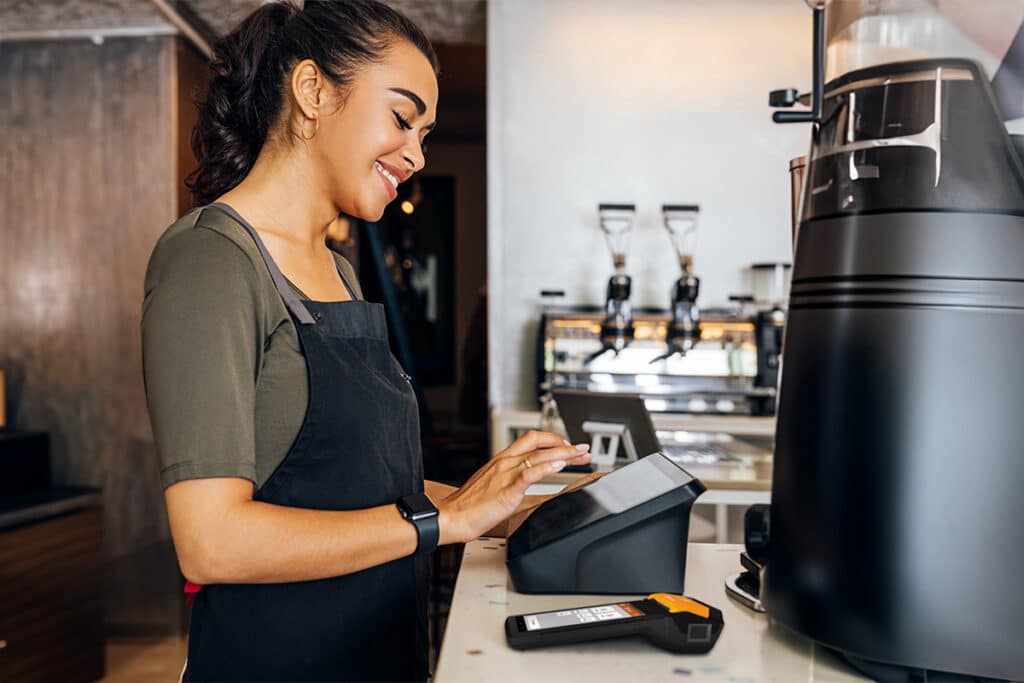 Woman at counter using pointer of sale terminal