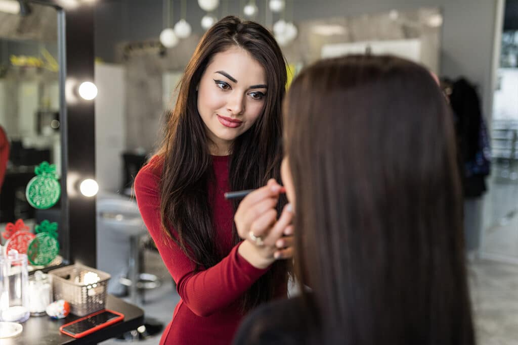 Makeup artist applying makeup to seated client