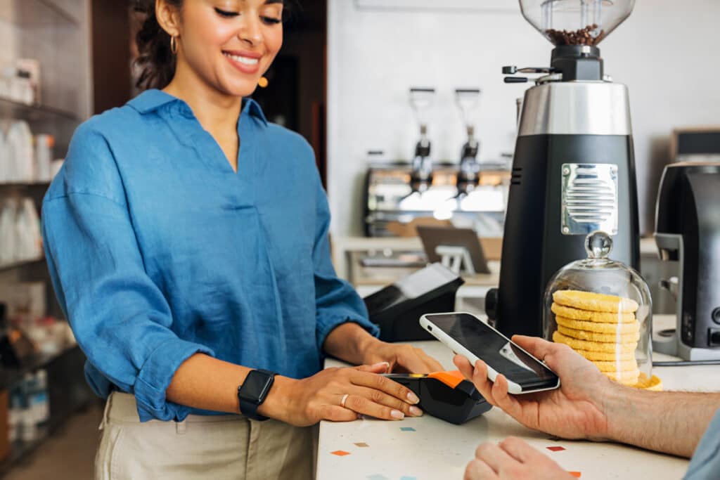 Barista accpeting a credit card payment from a customer's smartphone