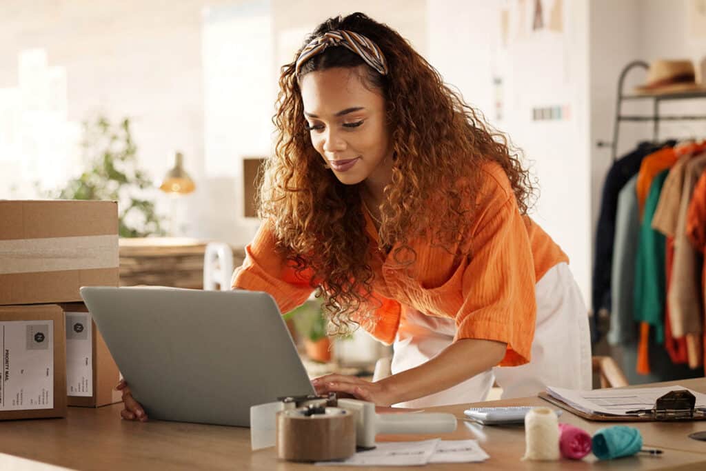An person hunched over their laptop in an orange shirt